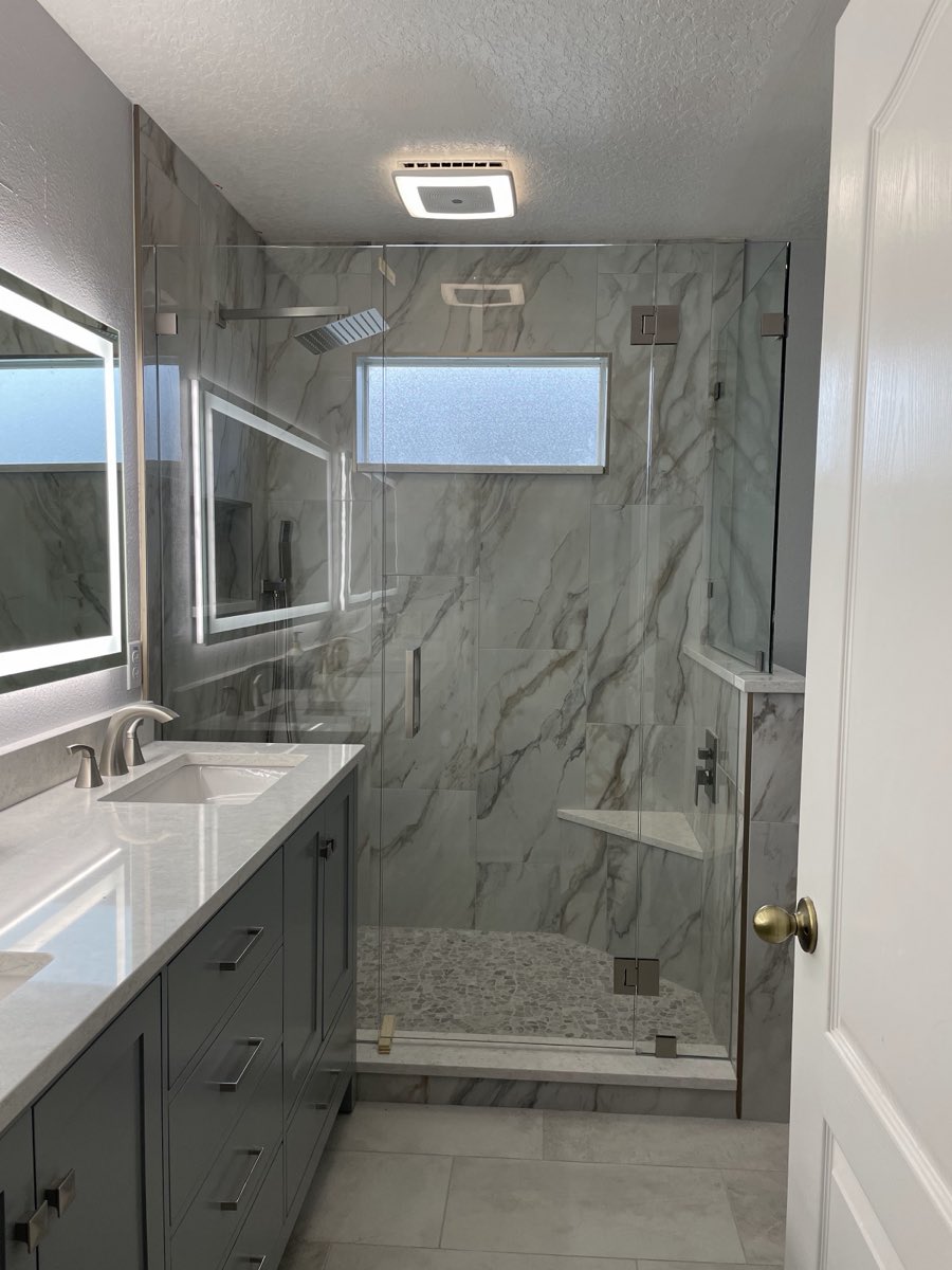 Marble-tile bathroom with double vanity and glass walk-in shower