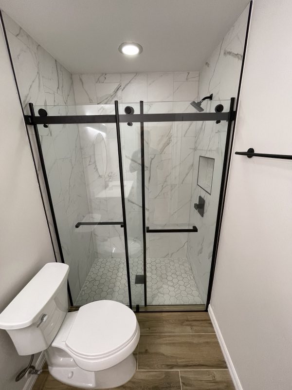 Glass walk-in shower with marble tile and hexagon floor